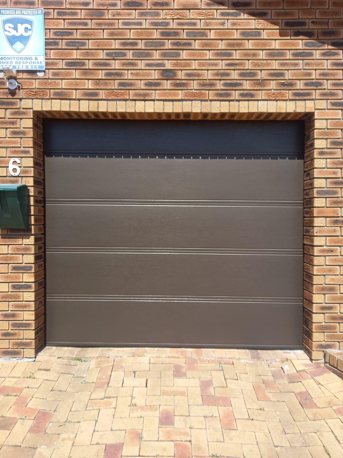 Bronze garage door matched to a face-brick facade