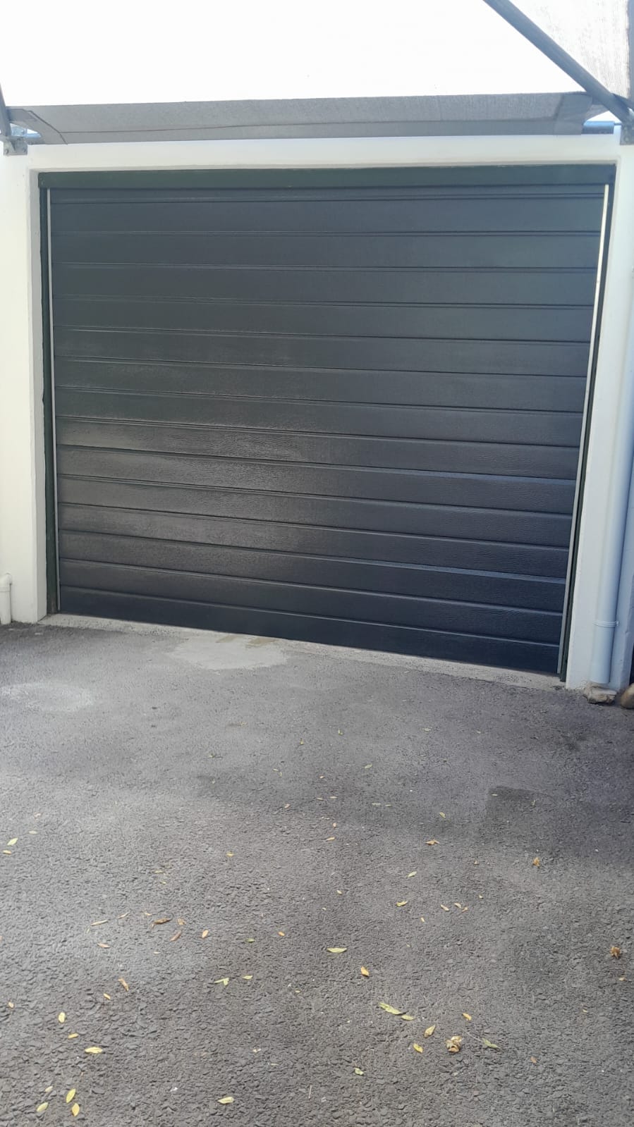 Charcoal garage door under a carport