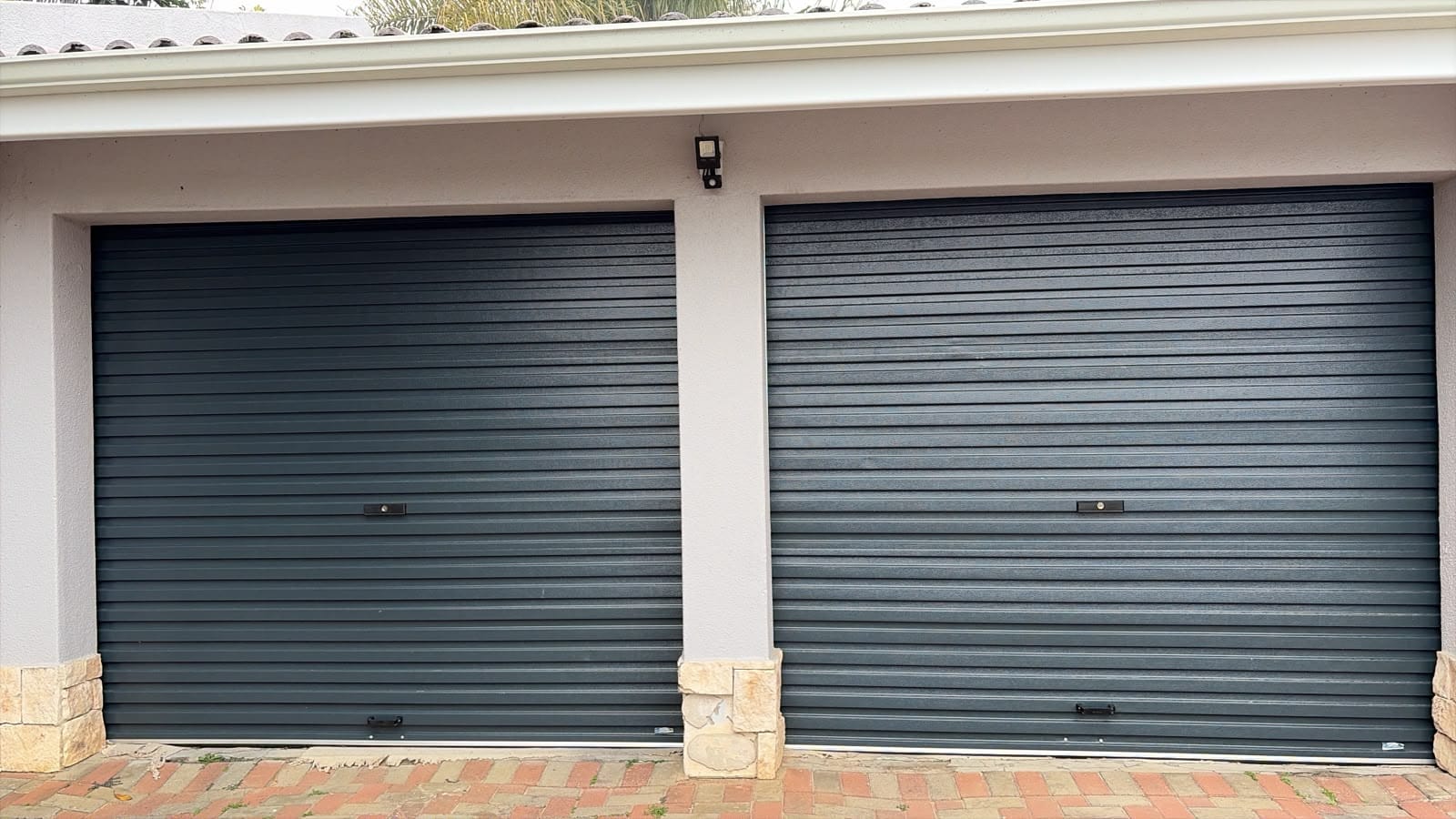 Two charcoal roller shutter garage doors installed side by side