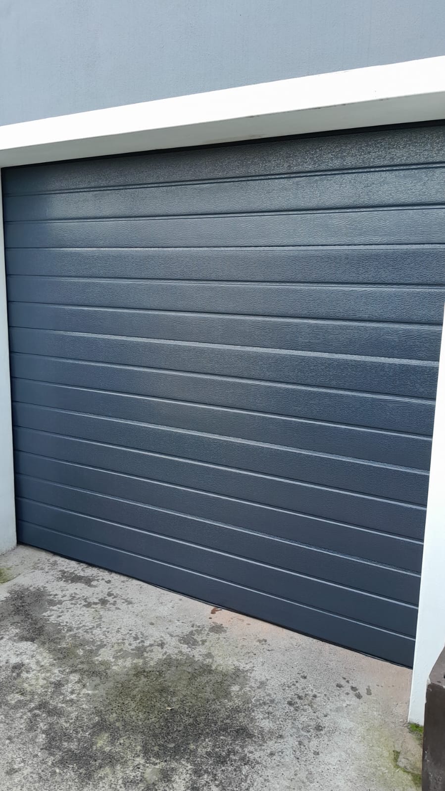 Charcoal sectional garage door with a textured woodgrain finish