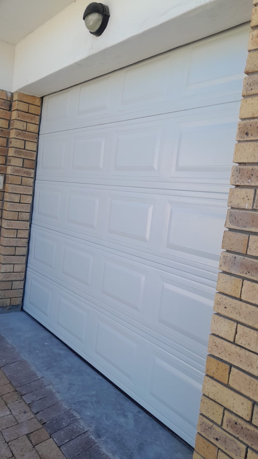 White raised-panel garage door on a face-brick home